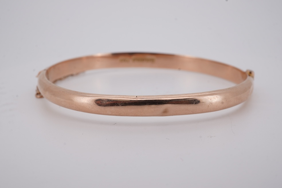 A George V part engraved 9ct gold hollow hinged bangle, Birmingham, 1911, interior diameter 57mm, 5.5 grams. Condition - poor